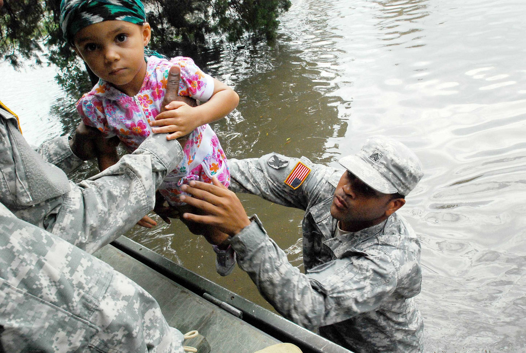 A soldier hands a child to another volunteer in a flood