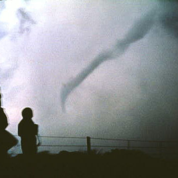 NC tornadoes landing in the background, as a couple stand in the foreground watching.